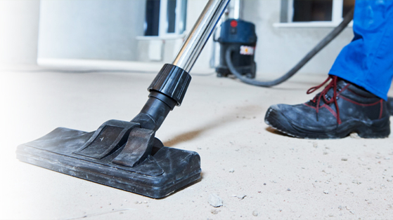 a person wearing black boots and vacuuming the floor in a post construction cleaning