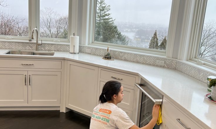 C4U professional cleaner polishing the glass of the beers fridge table while wearing a white shirt with the logo.