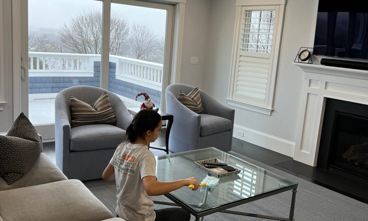 C4U professional cleaner polishing the glass coffee table while wearing a white shirt with the logo.