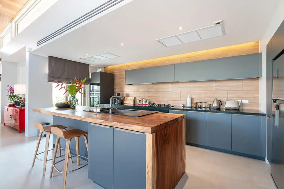 Modern kitchen interior with wooden countertops, blue cabinets, and pendant lighting.