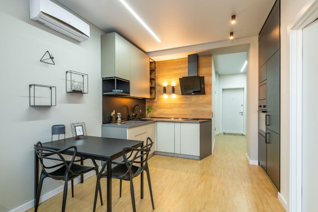 Modern kitchen interior with wooden accents, a sleek dining table set, wall-mounted decorations, and ambient lighting.