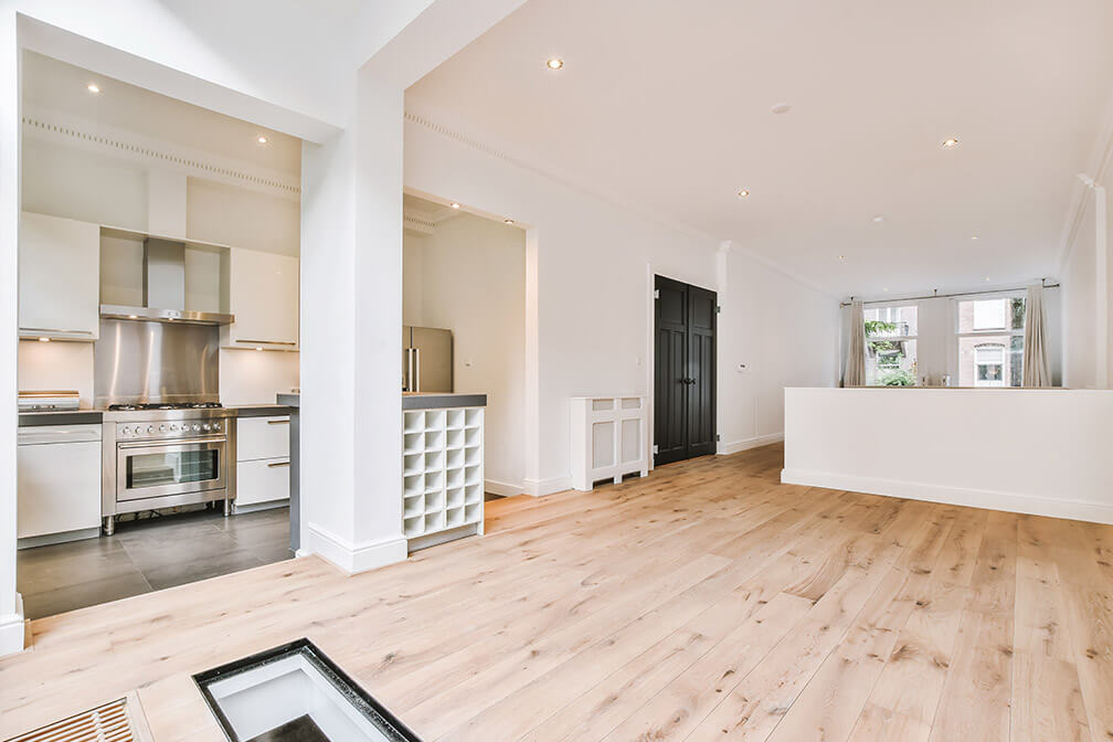 Modern kitchen interior with white cabinetry, wine rack, and light wooden flooring.